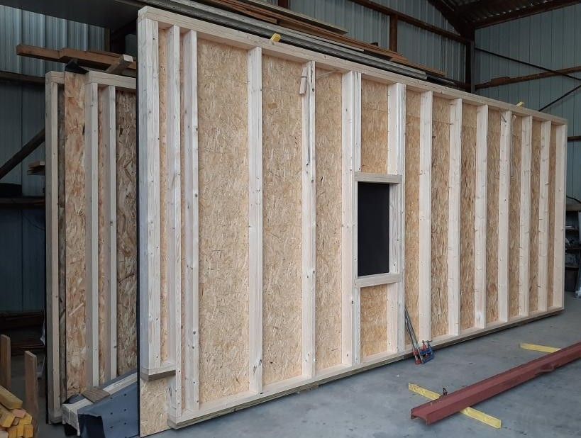 Sections de mur à ossature de bois avec une ouverture de fenêtre, à l'intérieur d'un bâtiment.