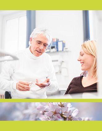 Ein Zahnarzt in einem weißen Rollkragenpullover berät einen Patienten in seiner Praxis