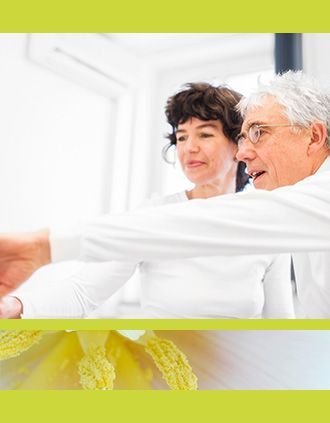 Zwei Personen in weißen Hemden zeigen in einem hellen Innenraum auf etwas außerhalb des Bildausschnitts.