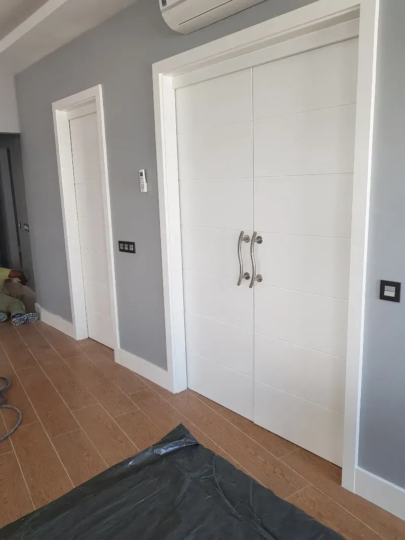 Un pasillo con puertas blancas y paredes grises.