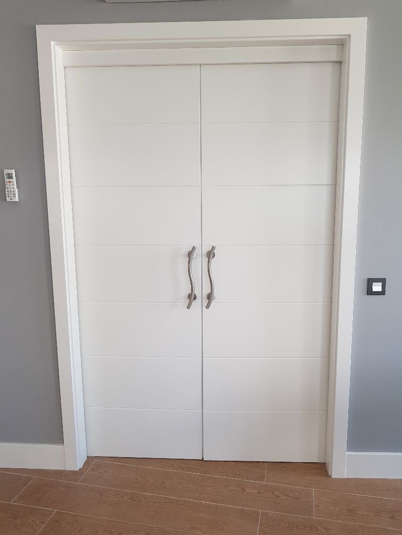 Un par de puertas dobles blancas en una habitación con paredes grises.