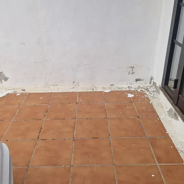 Una habitación con suelo de baldosas y una pared blanca.