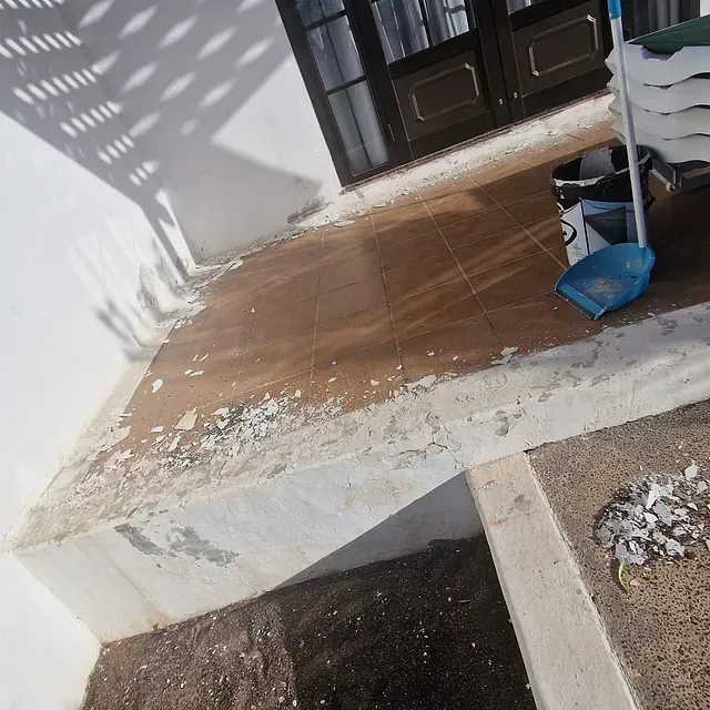 Una pala azul está sobre un suelo de baldosas.