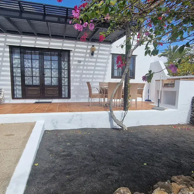 Una casa blanca con un patio y un árbol delante.
