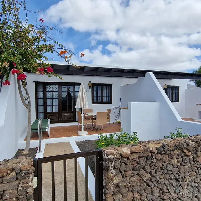 Una casa blanca con un muro de piedra que la rodea.
