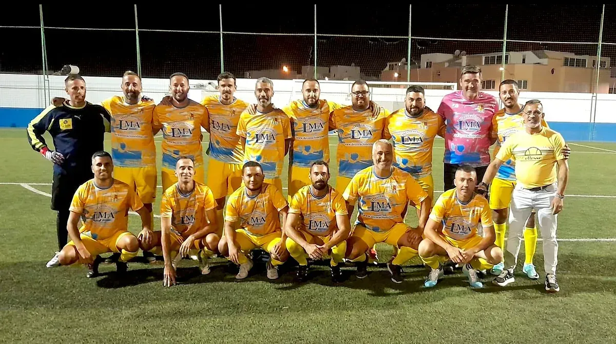 Un grupo de hombres posa para una fotografía en un campo de fútbol.