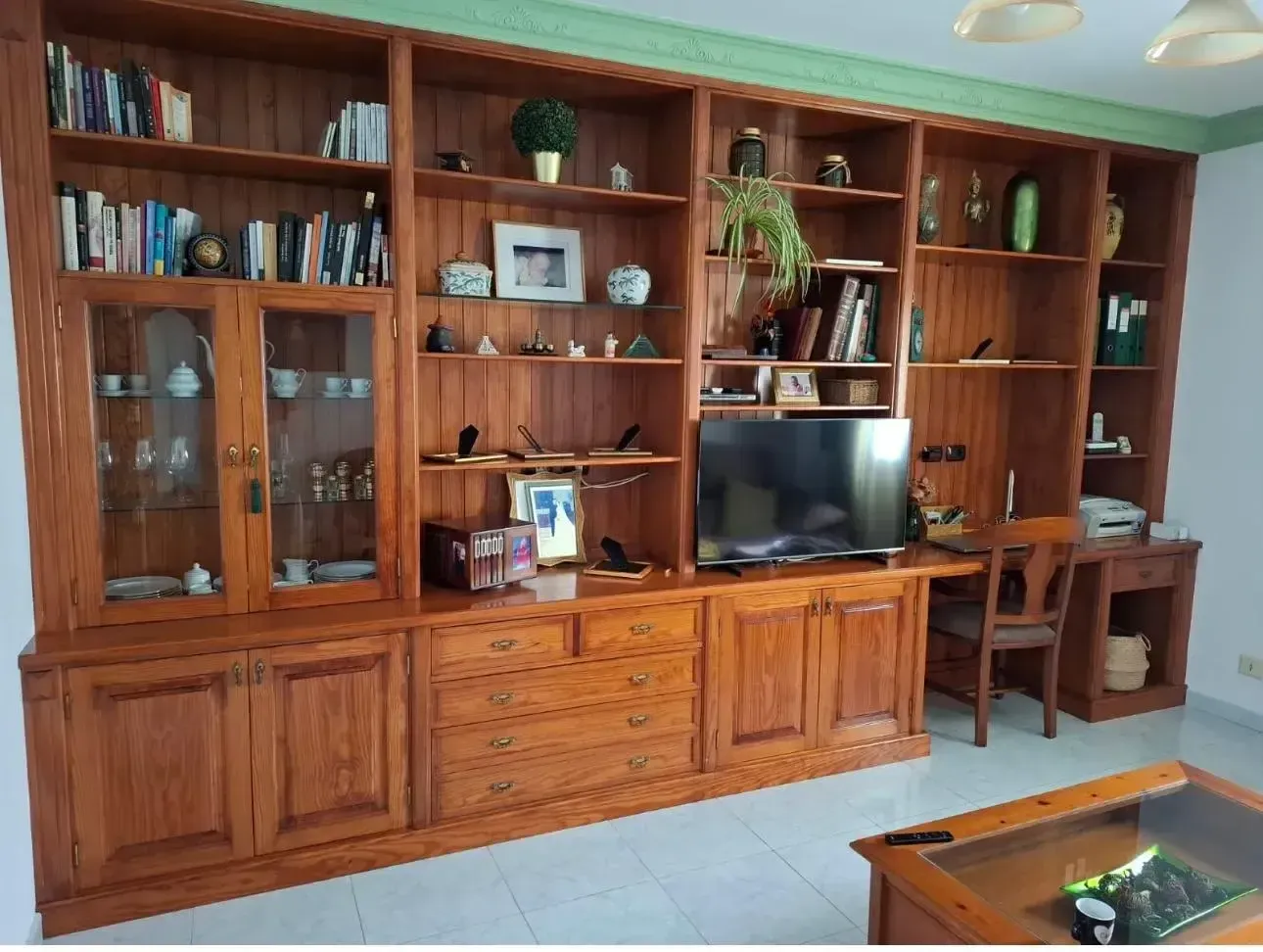 Una sala de estar con muchos estantes de madera y un televisor de pantalla plana.