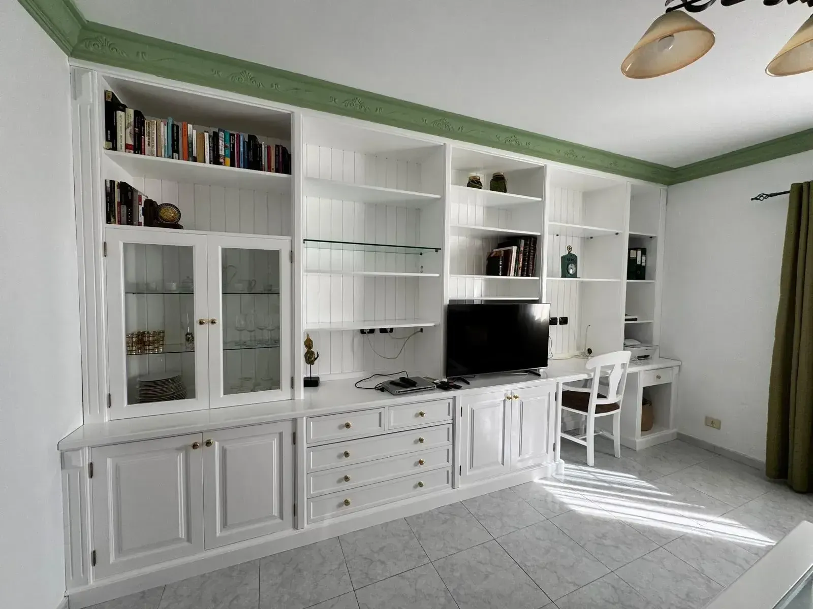 Una sala de estar con gabinetes blancos y un televisor de pantalla plana.