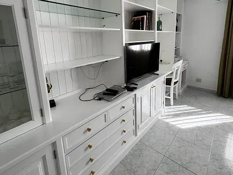 Una sala de estar con gabinetes blancos y un televisor de pantalla plana.