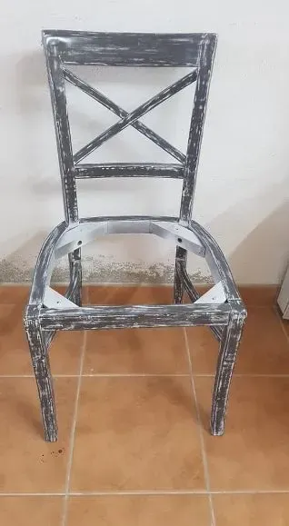 Una silla sin asiento está sentada sobre un suelo de baldosas.