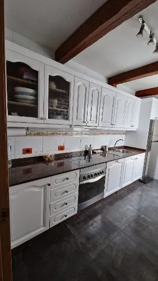 Una cocina con gabinetes blancos, una estufa, un fregadero y un refrigerador.