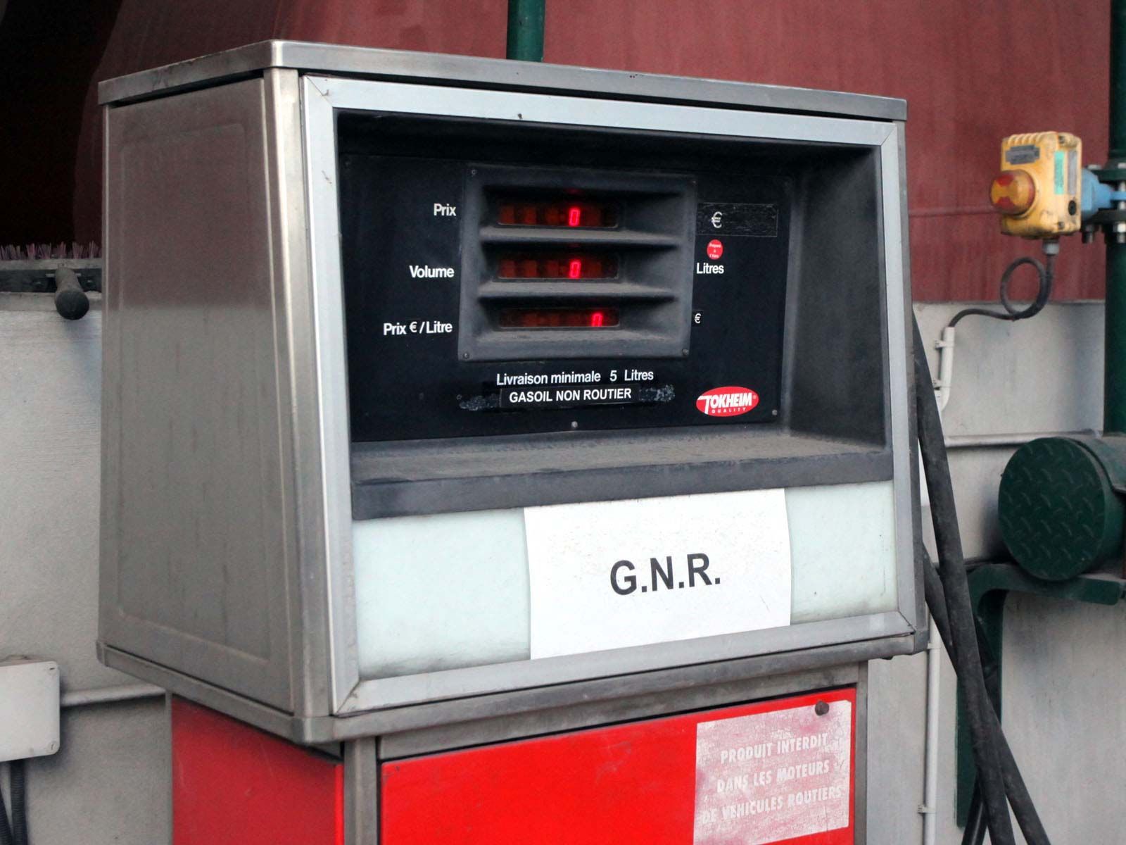 Une pompe à carburant portant l'étiquette GNR, dotée d'un affichage numérique noir, d'un cadre en métal et d'une base rouge.