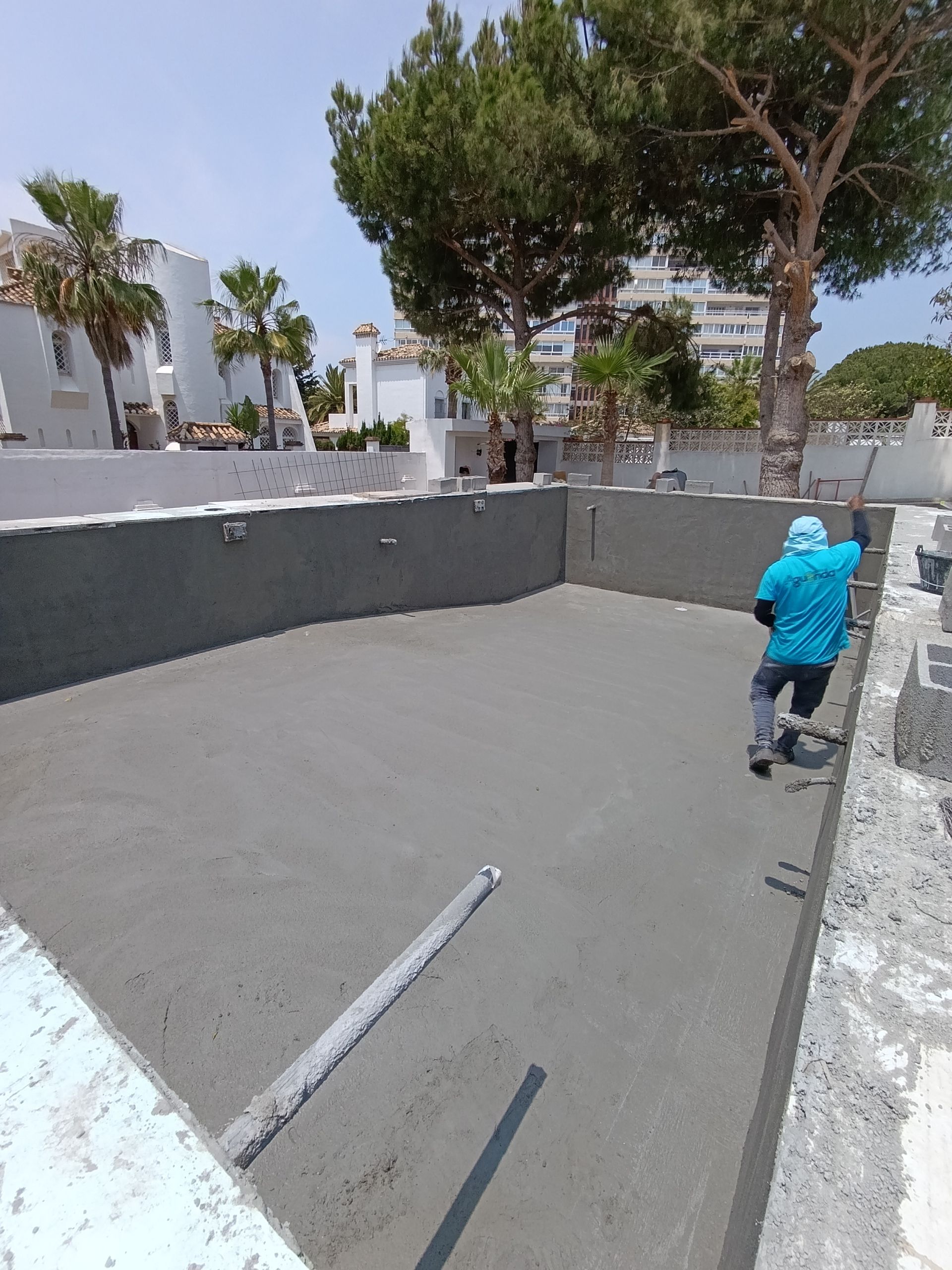 Un hombre con una camisa azul está trabajando en una piscina.
