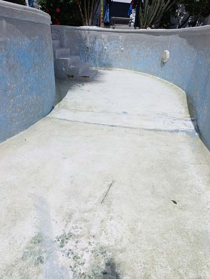 Piscina vacía, de color azul claro, con escalones que muestran el desgaste de la superficie.