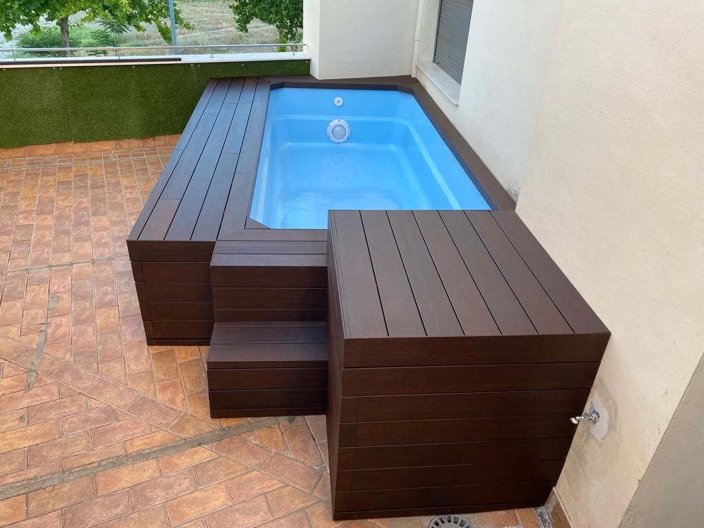 Una pequeña piscina está rodeada por una terraza de madera y escaleras.