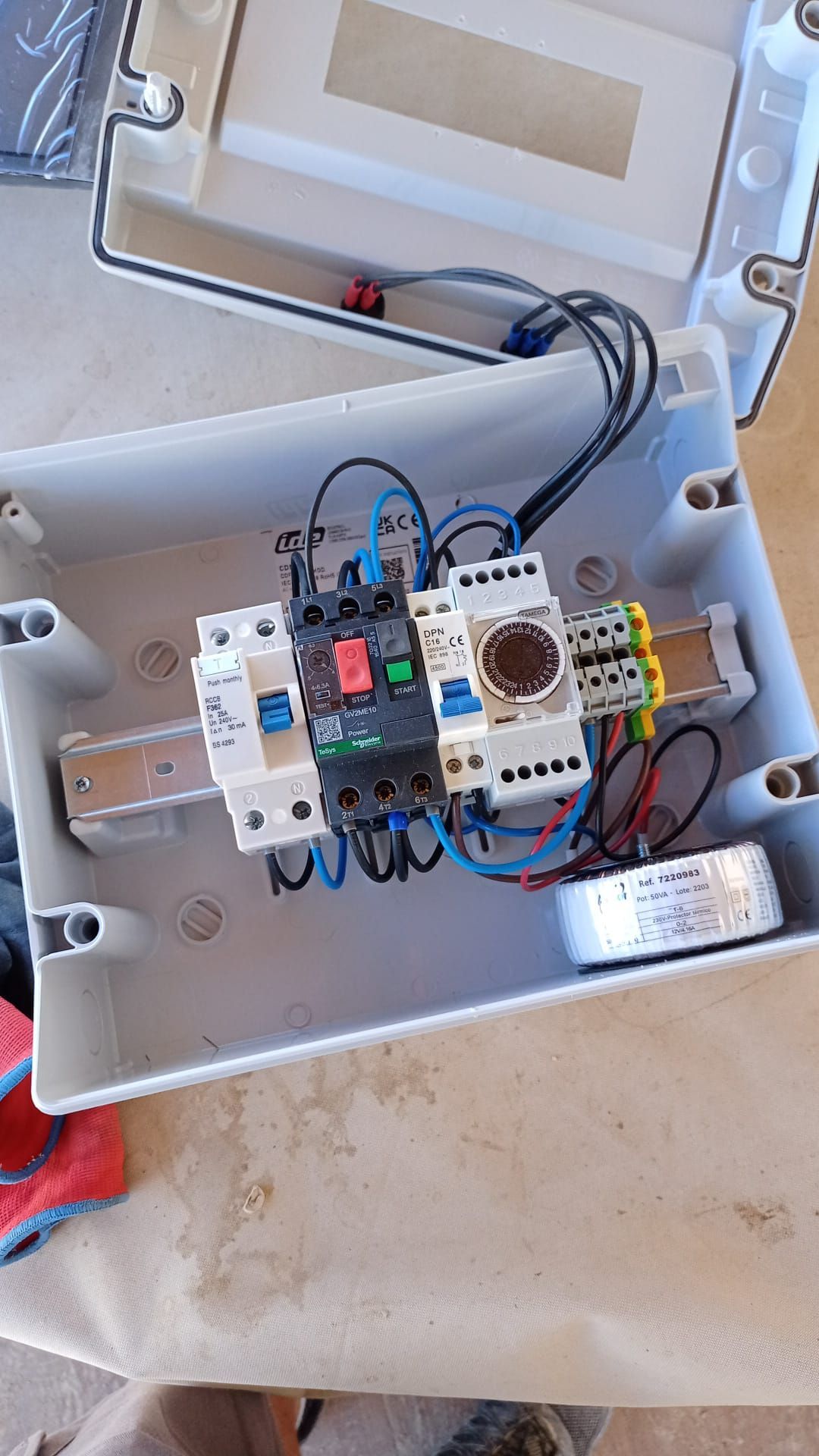 Cuadro eléctrico de control con diversos componentes, dentro de caja de plástico gris.