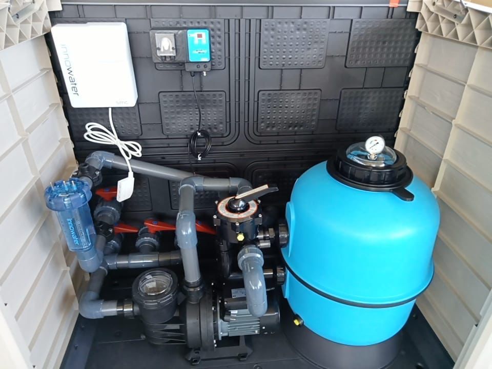 Equipo de piscina dentro de una caja de almacenamiento de plástico: bomba, filtro y dispensador de productos químicos.