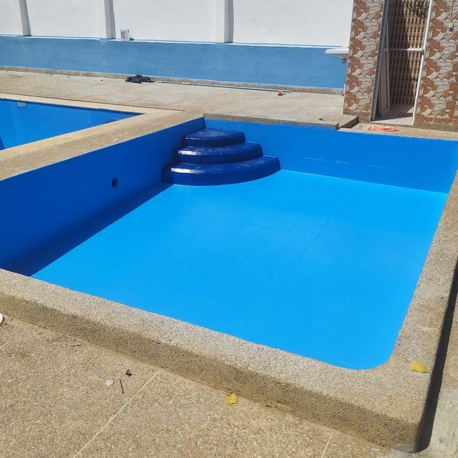 Piscina pintada de azul con escalones, borde de hormigón y paredes azules.