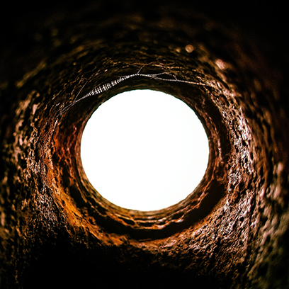 Levant les yeux depuis l'intérieur d'un tunnel sombre et accidenté vers une ouverture circulaire lumineuse