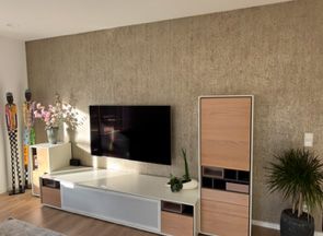 Wohnzimmer mit Wohnwand vor einer strukturierten Wand.