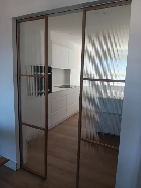Acogedora sala de estar con estanterías empotradas de color beige, elementos decorativos, una lámpara y un sofá contra una pared con iluminación tenue.