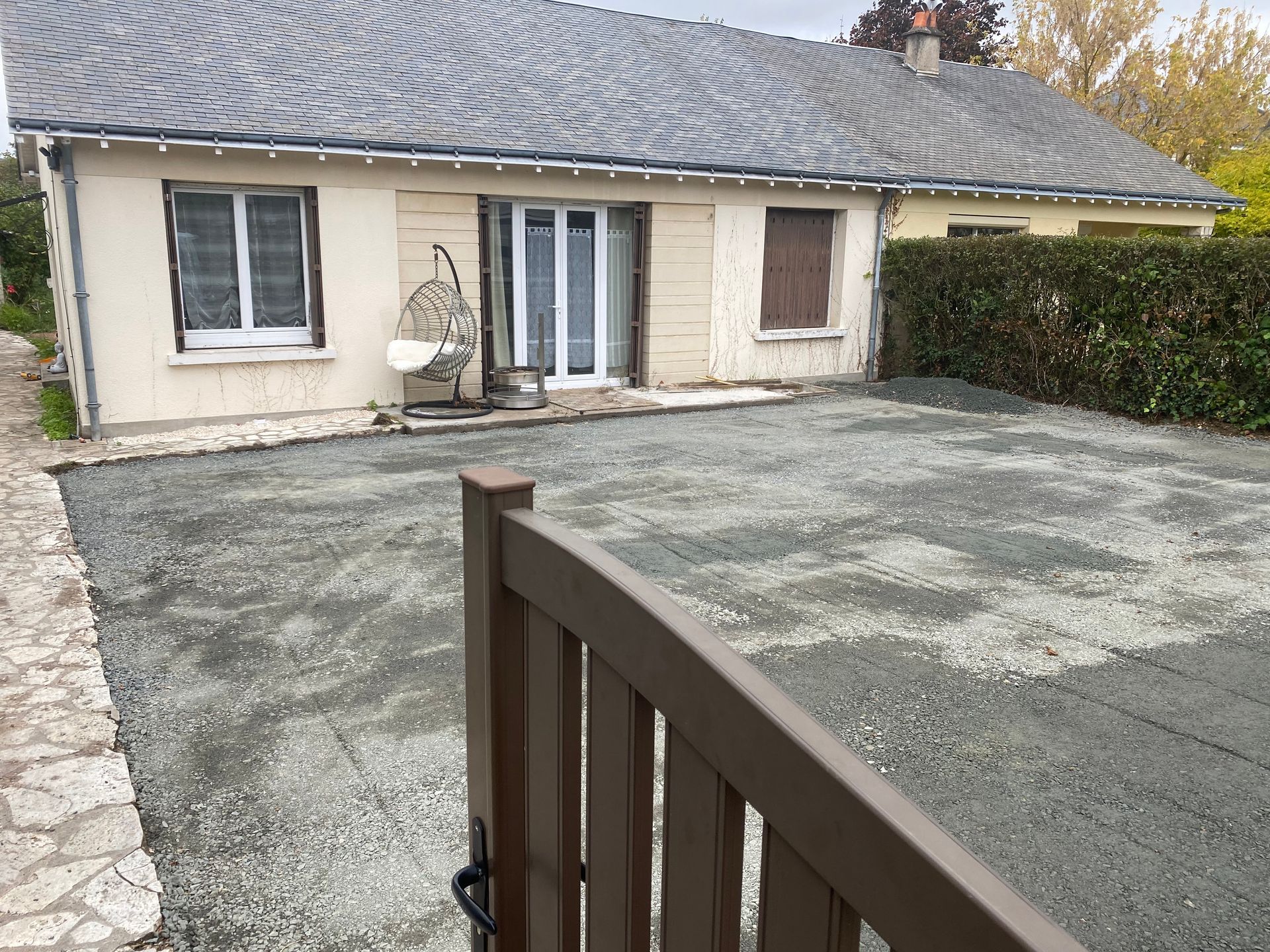 Vue depuis l'entrée du portail d'un terrassement paysager abouti avec derrière la maison individuelle