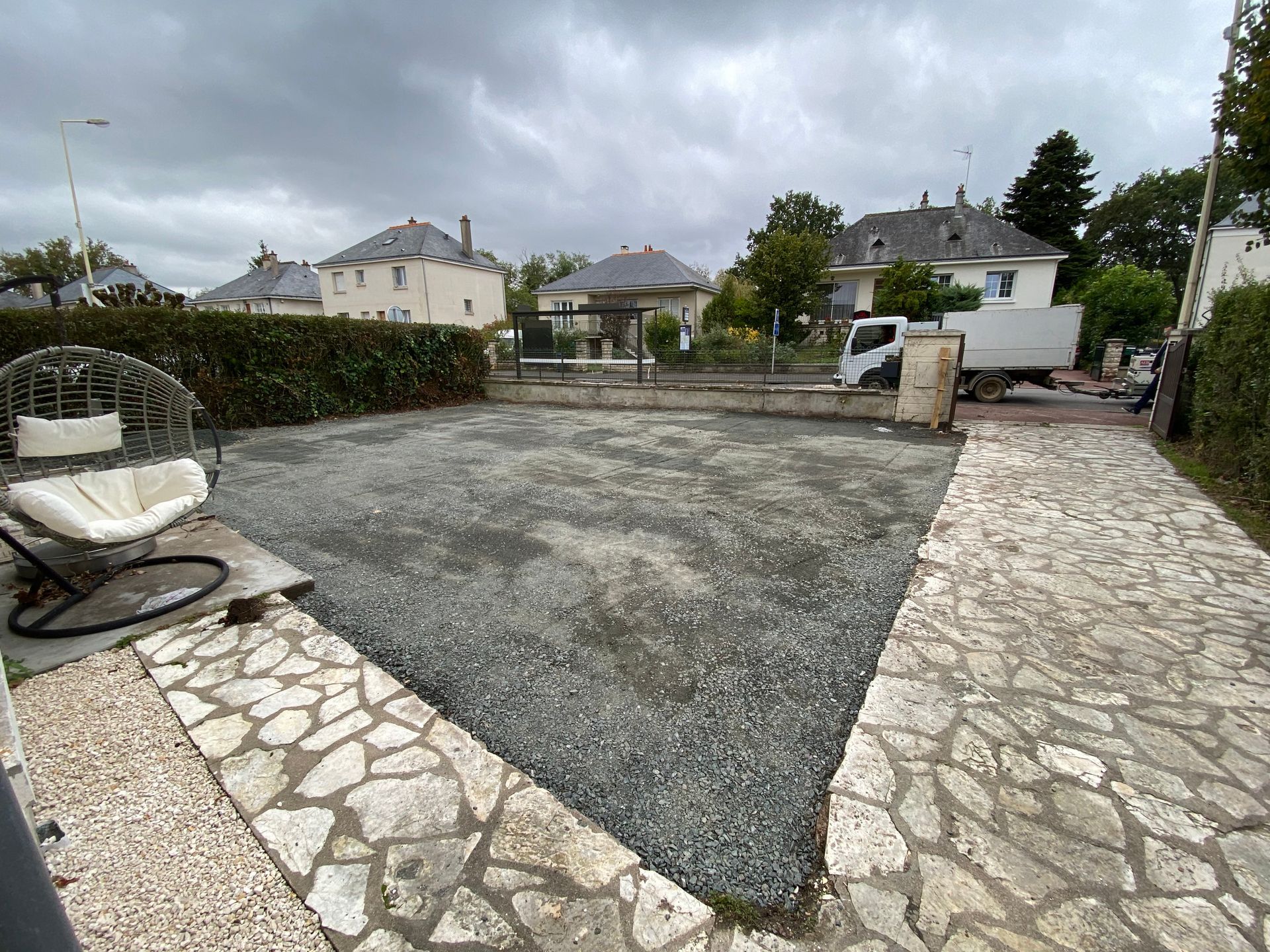 Vue d'un terrain ayant bénéficié d'un terrassement paysager, avec un revêtement gravillonné et un contour dallé