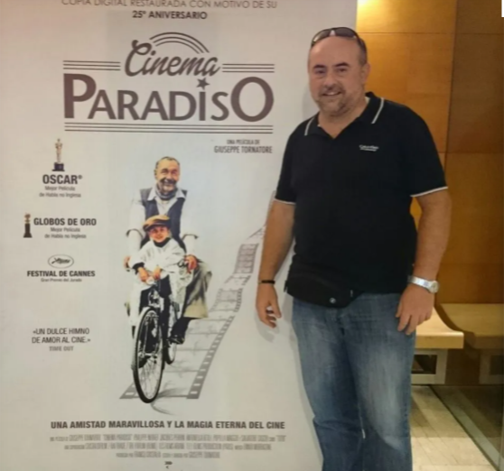 Un hombre se encuentra frente a un cartel de Cinema Paradiso.