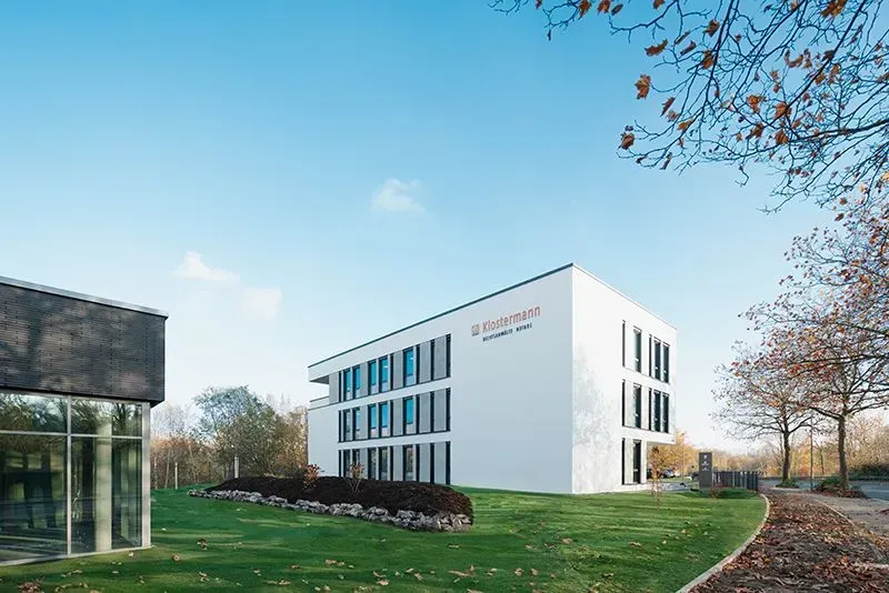 Ein großes weißes Gebäude steht auf einem üppigen grünen Feld. Foto von der Metallbau Schilloh GmbH