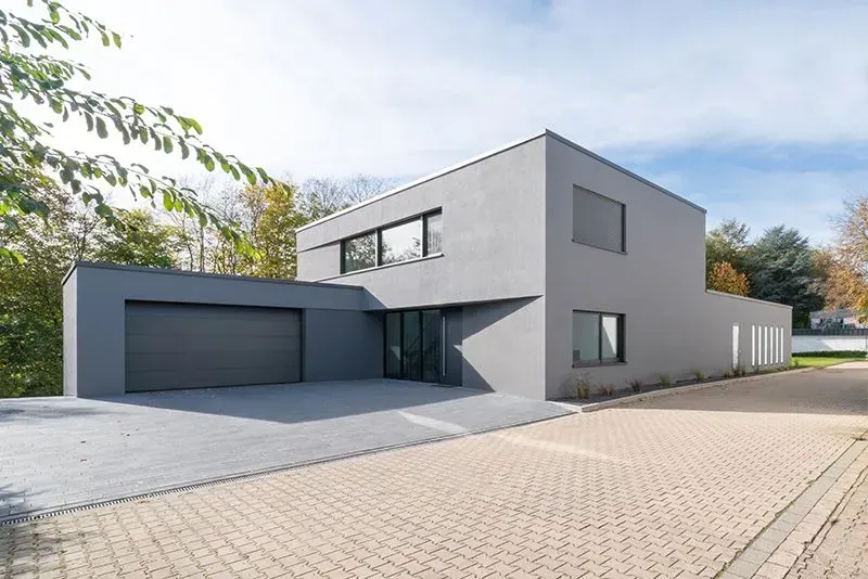 Ein großes graues Haus mit einer Garage und einer Einfahrt. Foto von der Metallbau Schilloh GmbH
