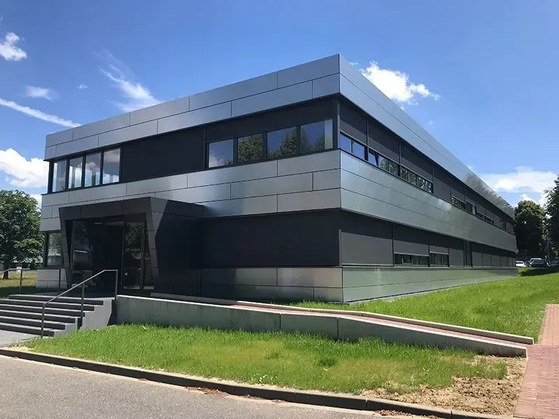 Auf einer üppigen grünen Wiese steht ein großes Gebäude mit einer Treppe, die nach oben führt. Foto von der Metallbau Schilloh GmbH