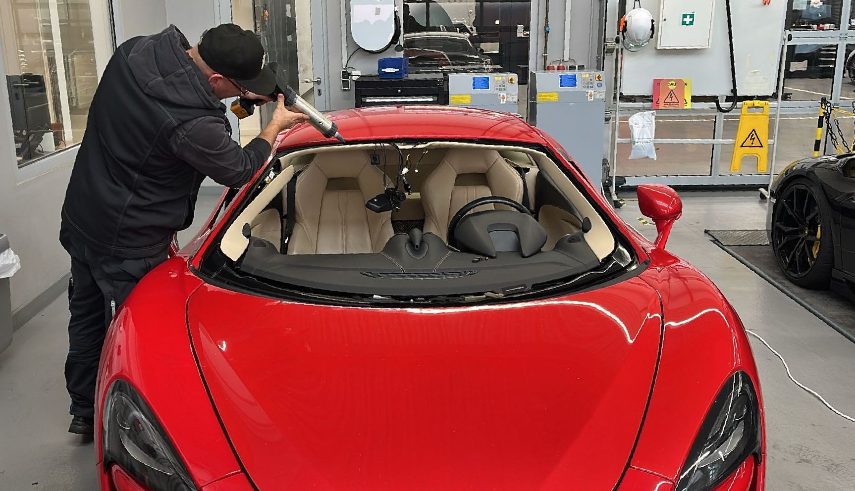 Ein Mann arbeitet in einer Garage an einem roten Sportwagen.