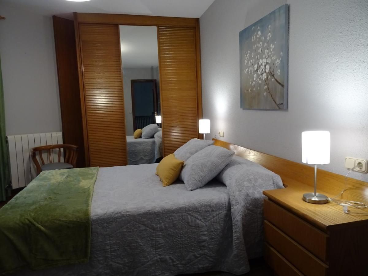 Dormitorio con cama, armario de madera y mesita de noche. Las paredes son grises y hay un cuadro sobre la cama.