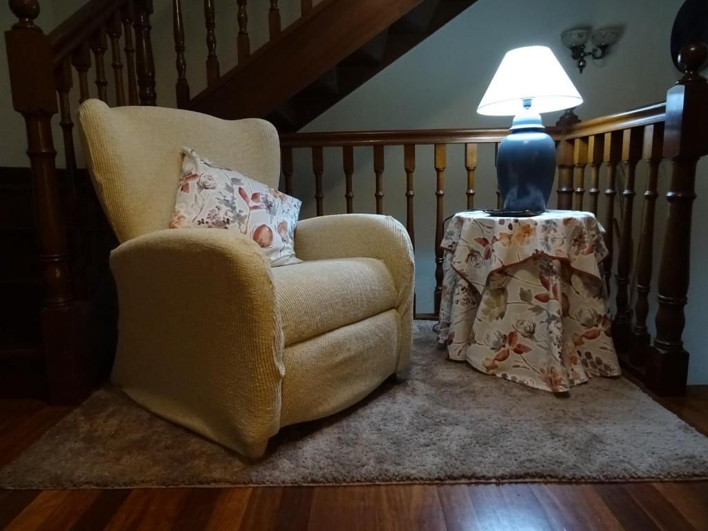 Sillón reclinable de color crema, almohada estampada, lámpara en la mesa auxiliar.