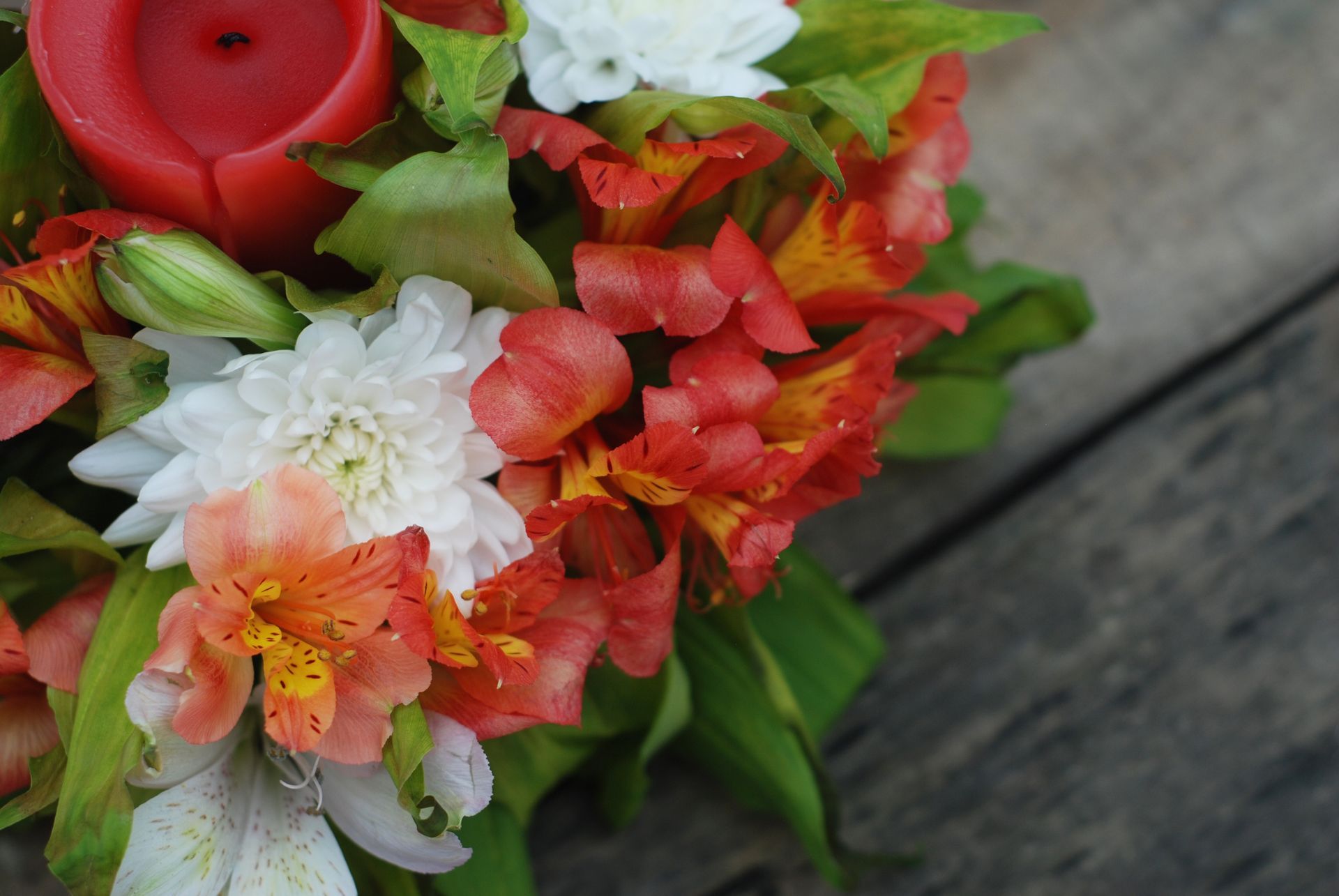 Un ramo de flores con una vela roja en el medio.
