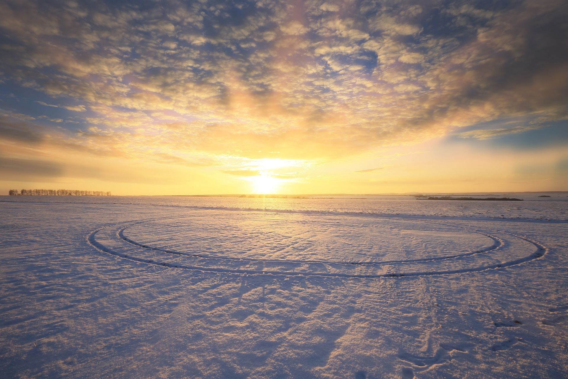 Un campo nevado con una puesta de sol al fondo