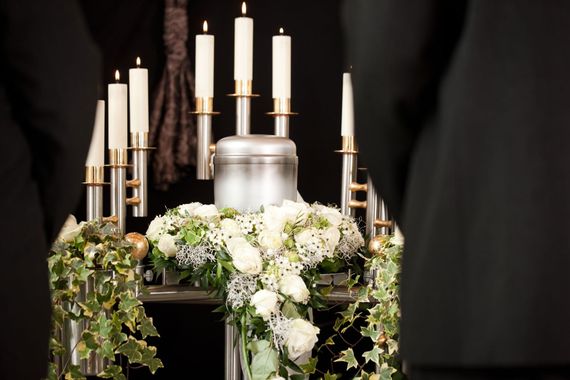 Una urna de plata rodeada de flores blancas y velas.