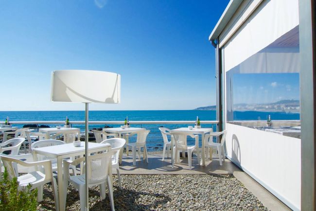 Un patio con mesas y sillas con vista al mar.