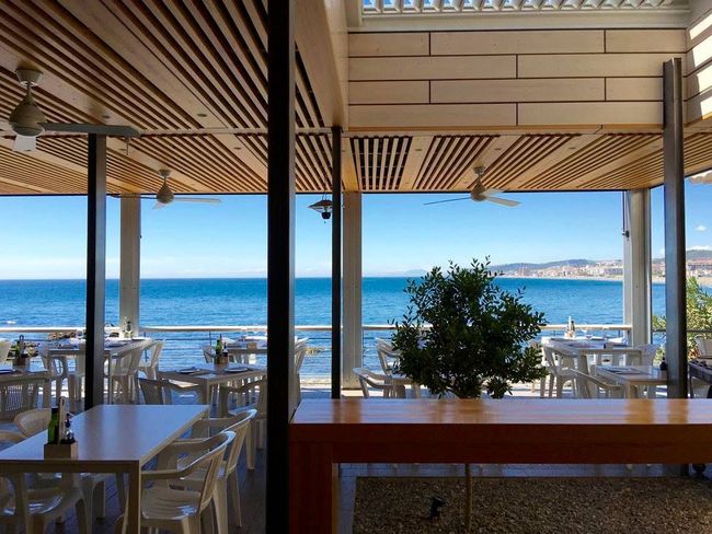 Un restaurante con mesas y sillas con vista al mar.