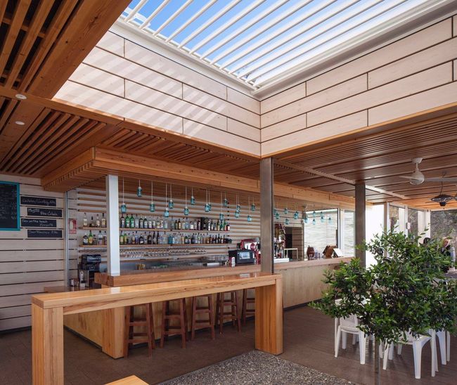 Un restaurante con una gran mesa de madera y taburetes.