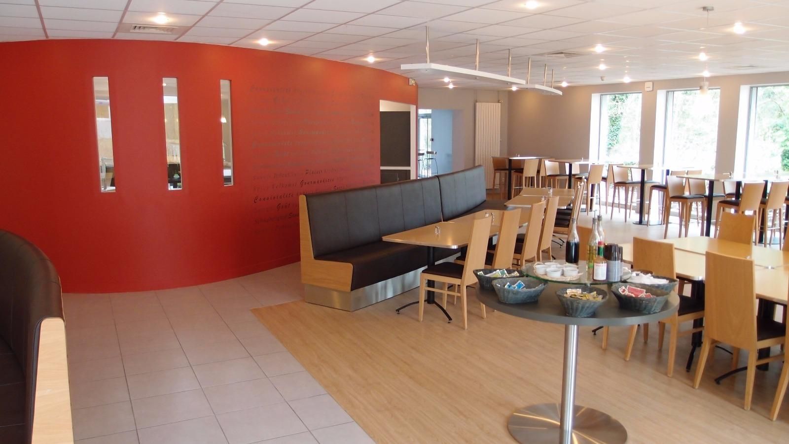Salle à manger avec longs bancs, tables et espaces pour le service