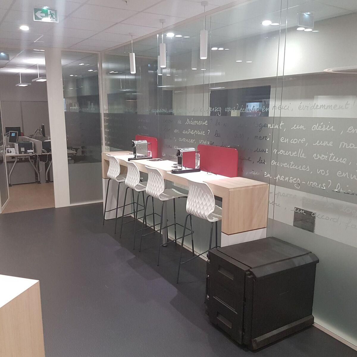 Meuble long en bois avec 4 chaises du même côté et 2 cafetières à dosettes