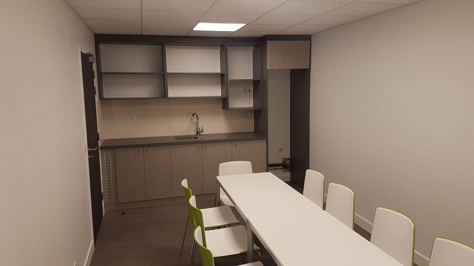 Grand espace dans une cuisine avec table et meuble avec de nombreux rangements et un accès à l'eau