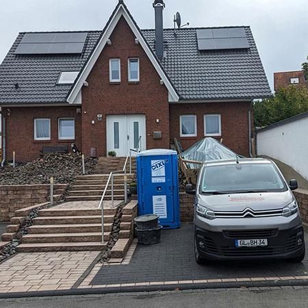 Ein Lieferwagen steht vor einem großen Backsteinhaus.