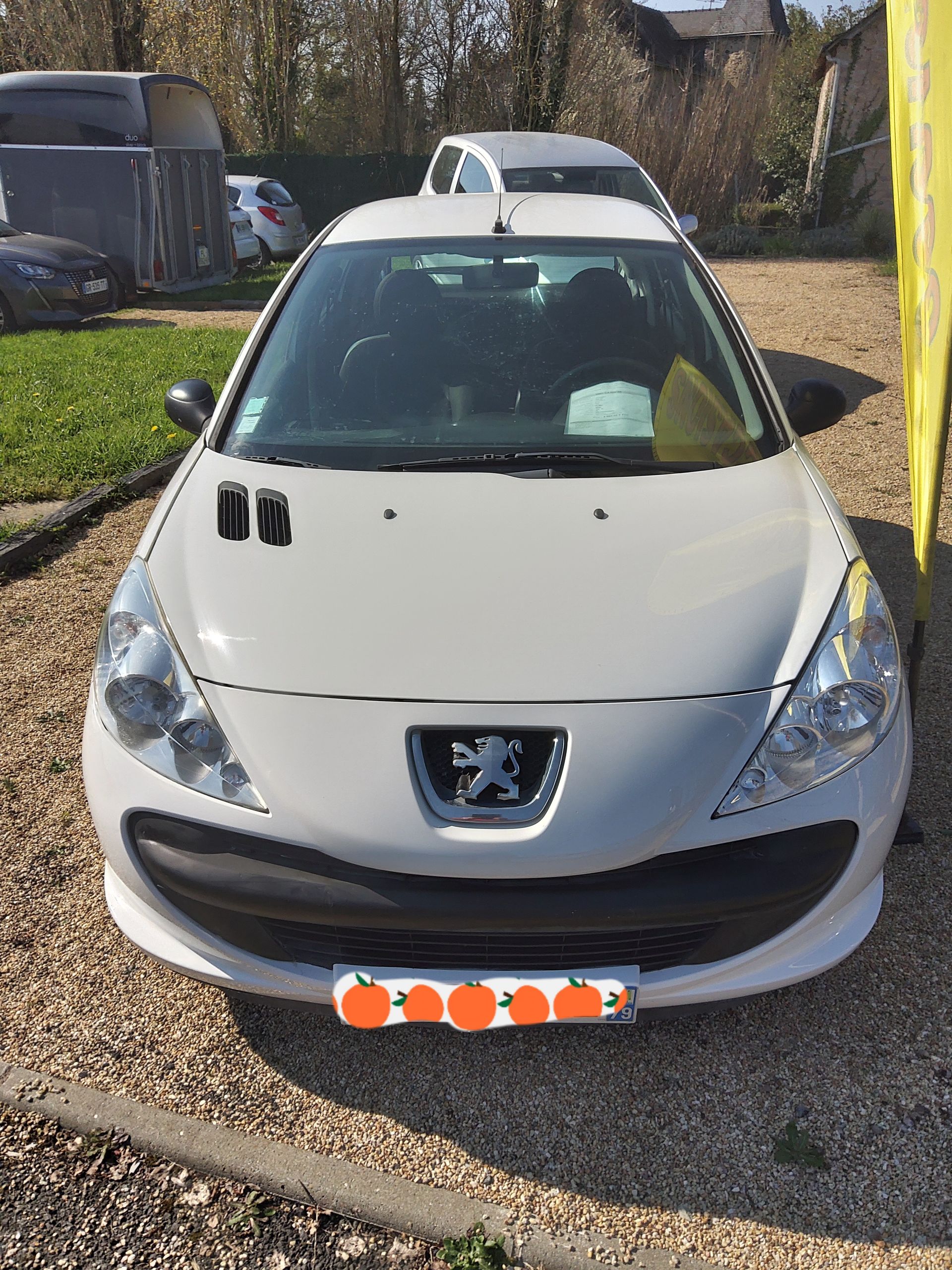 Une Peugeot à hayon gris clair garée sur un parking gravillonné