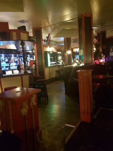 Schlichtes Barinterieur mit Holzsäulen, verspiegelten Wänden und leuchtenden Vitrinen.