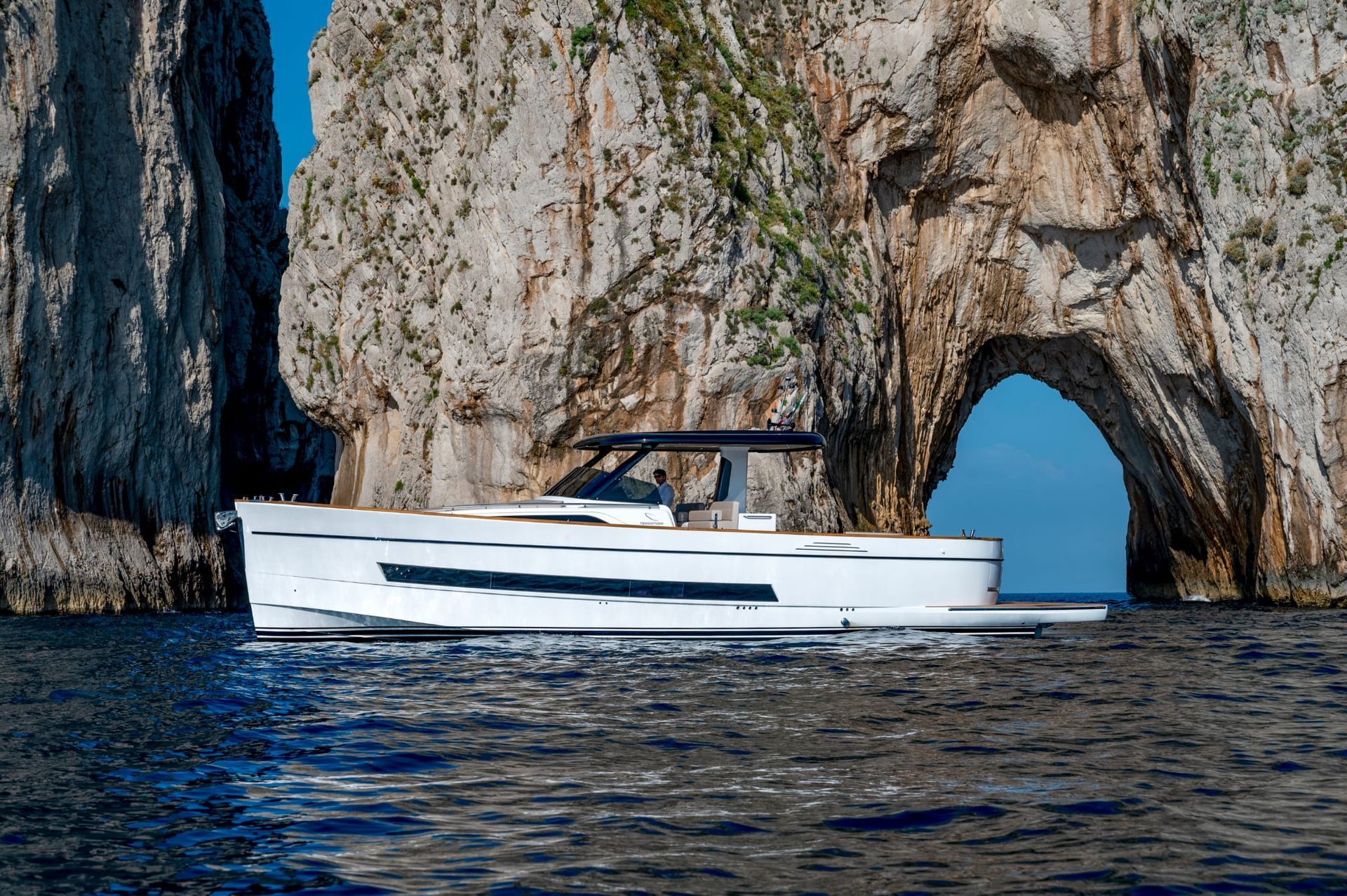 A boat is floating in the water near Faraglioni rocks in Capri