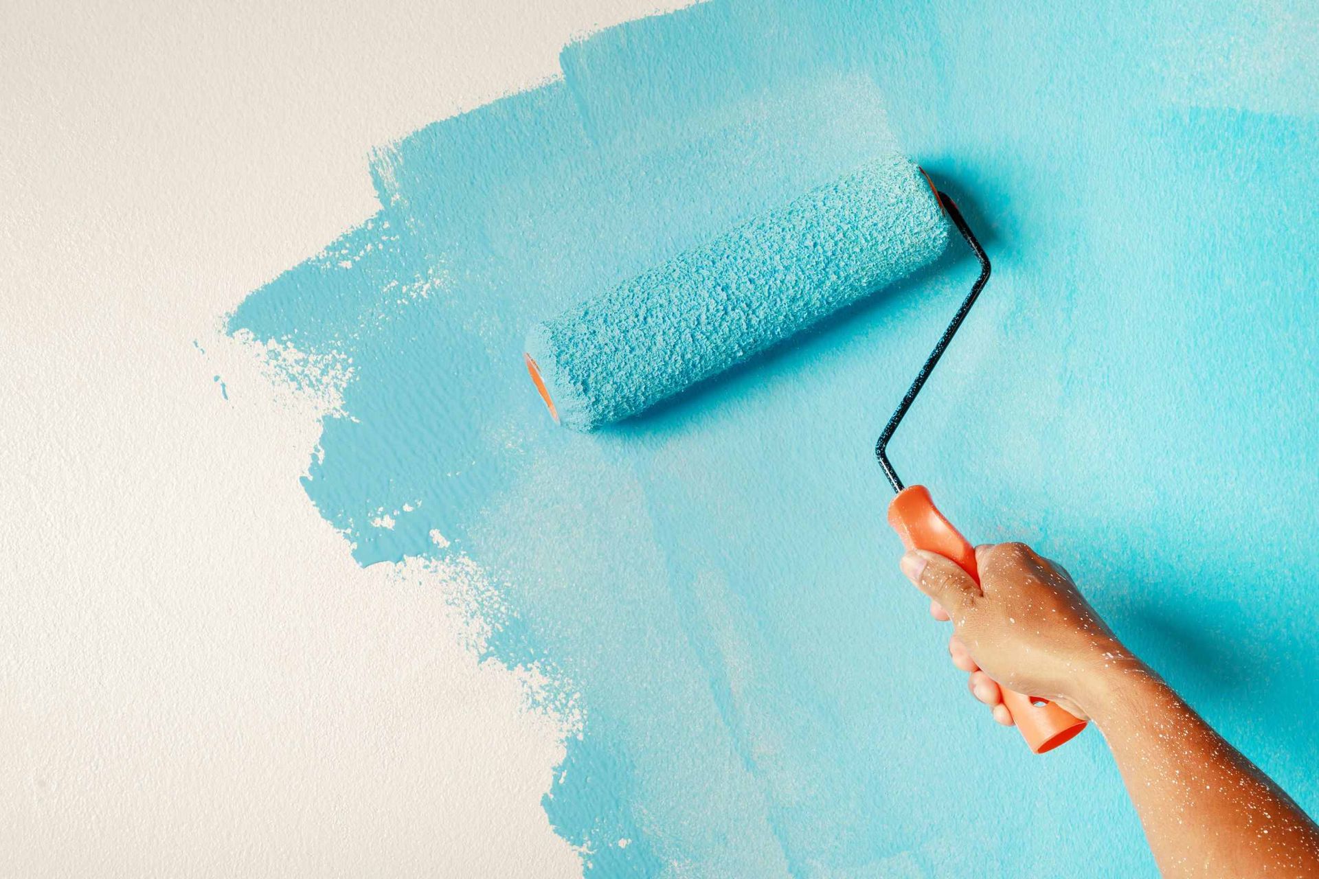 Una persona está pintando una pared con un rodillo de pintura azul.