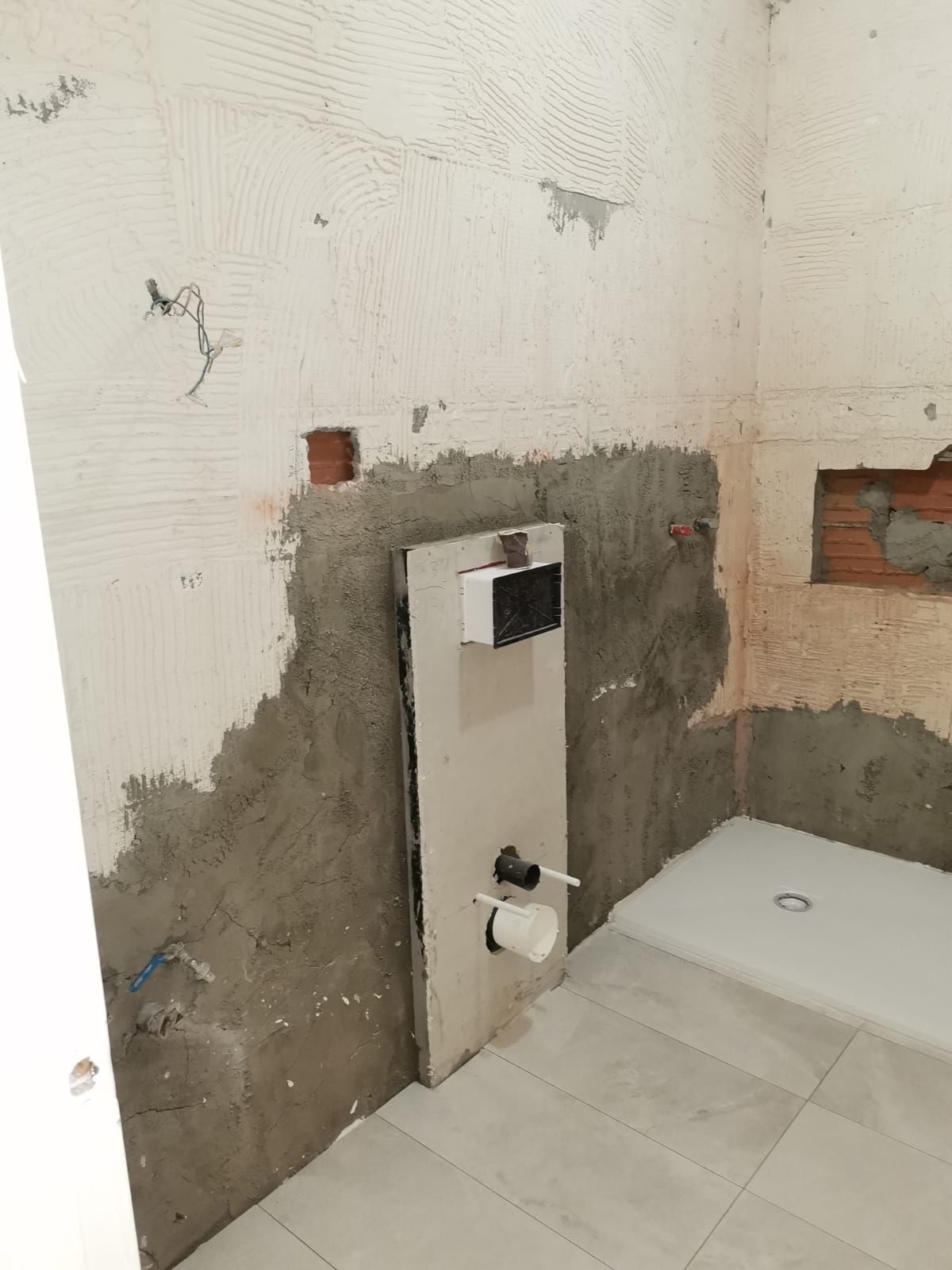 Un baño en construcción con inodoro y cabina de ducha.