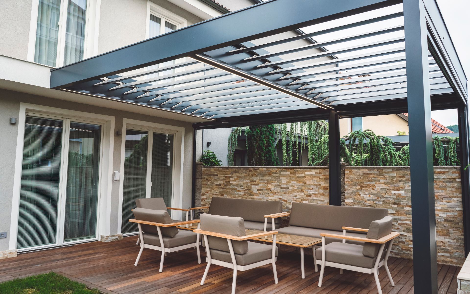 Un patio con un sofá y sillas bajo una pérgola.